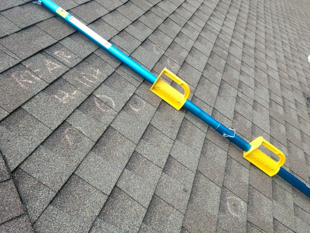 Measuring equipment resting on roof shingles